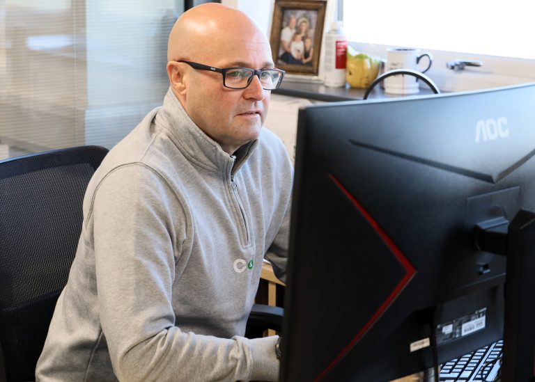 C&R consultant reviewing project plans at a desktop computer in the office — representing our consultancy service.