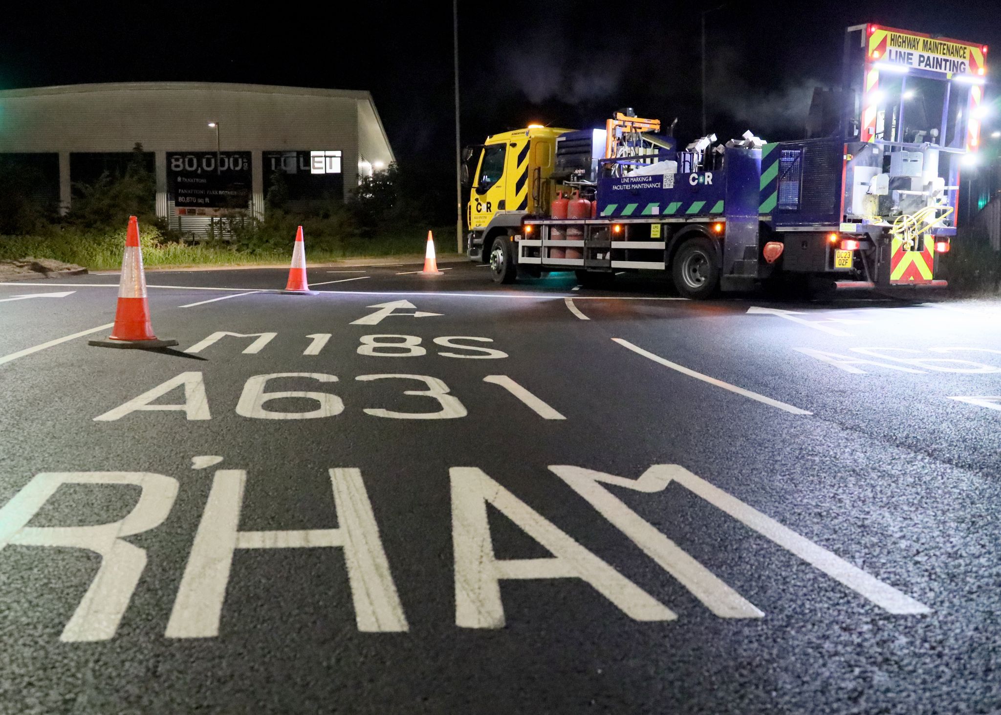 Car park & external line marking at night—truck marking with ‘M18S’ arrow and cones.