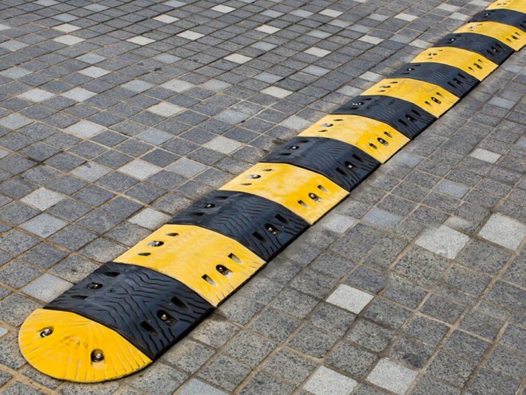 Black-and-yellow modular speed ramp bolted to block-paved surface — example of minor civils & street furniture installation.